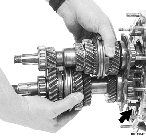 Slide shafts with gears and forks out of differential housing, leaving 1st - 2nd gear selector rod in transmission case.
NOTE-
Check the number and thickness of shims (arrow) between differential housing and bearing flange. This shimmed surface controls the pinion shaft depth. If no repairs are being carried out on the differnetial bearing or the differential, the exact shim pack should be reinstalled.
Manual Transmission–Controls and Case
page 340-20